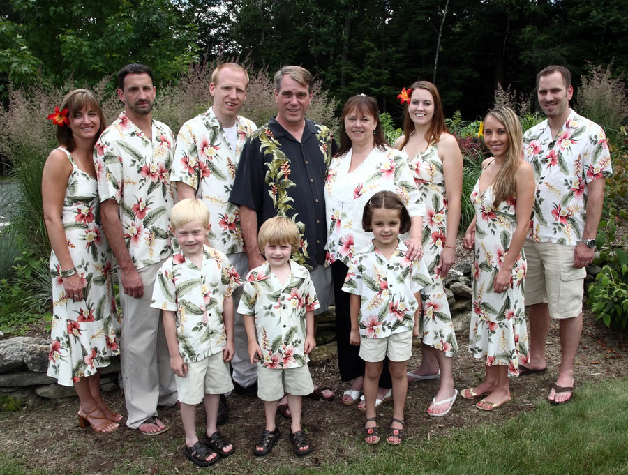 The family is dressed in matching white hawaiian shirts with pink and green floral patterns.